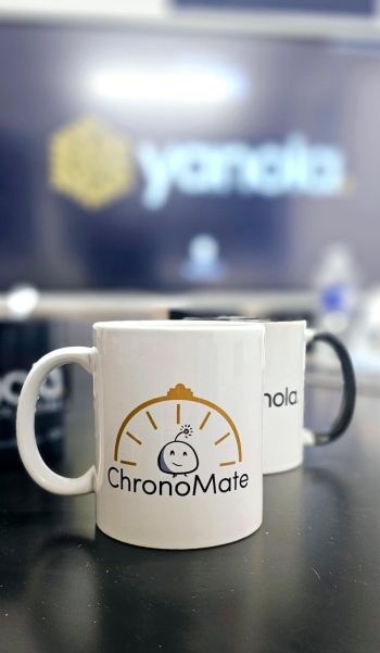 Chronomate est édité par l'agence digitale Yanola Deux tasses en premier plan, sur la première est écrit "Chronomate". En fond, il est écrit "Yanola"